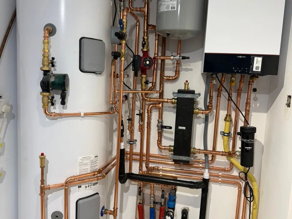 Wall-hung boiler, low loss header, pump and magnetic filter with clipped copper pipework beside an unvented cylinder