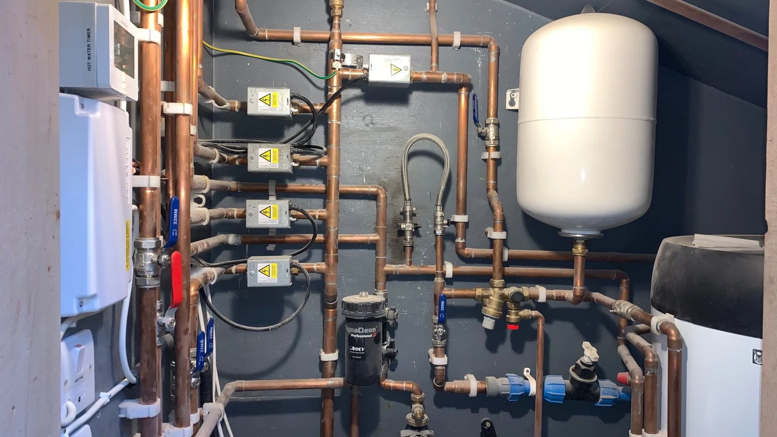 Heating pipework with zone valve actuators, an expansion vessel and a MagnaClean filter beside an unvented cylinder