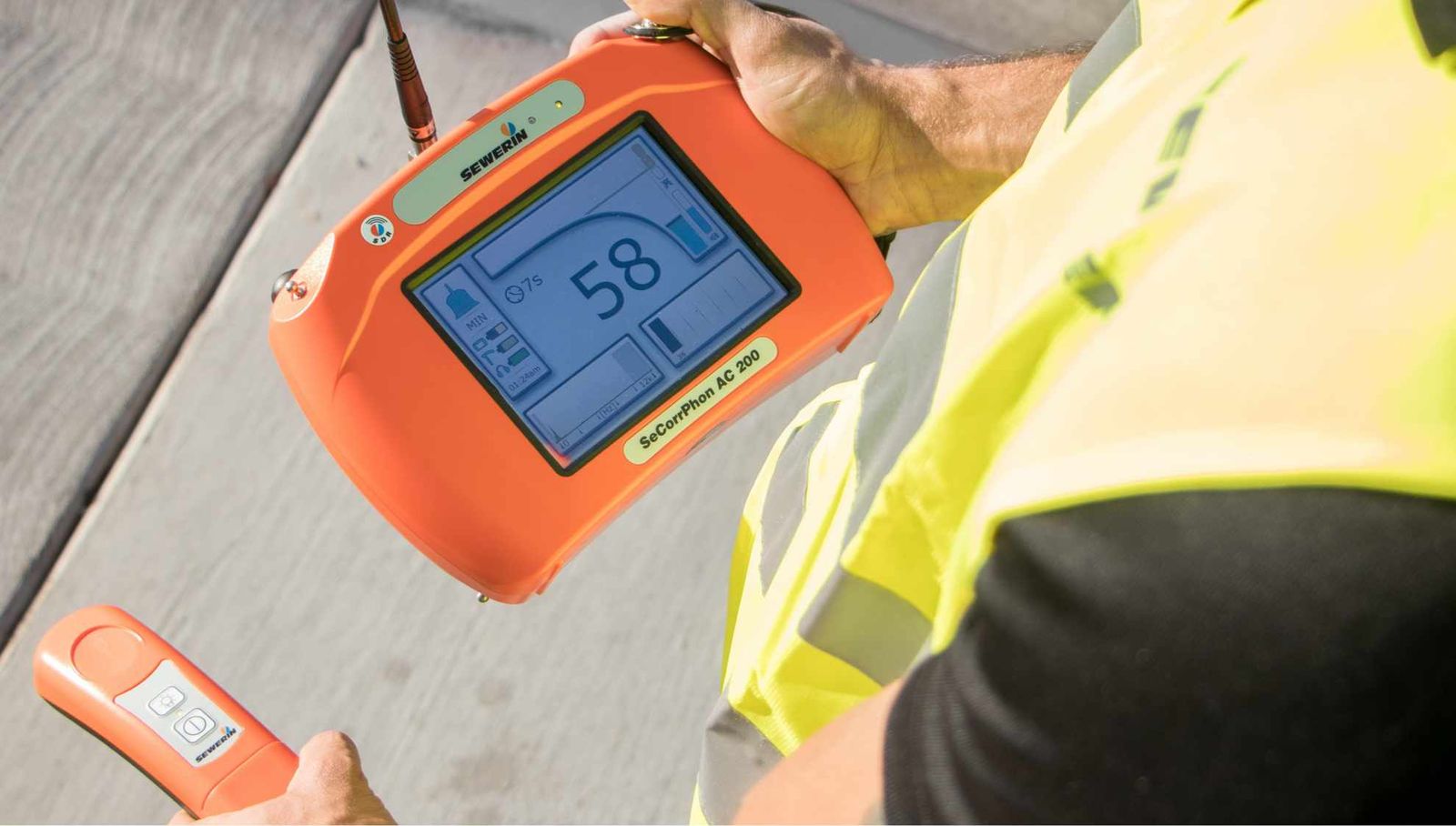Engineer using a handheld acoustic leak detector outdoors