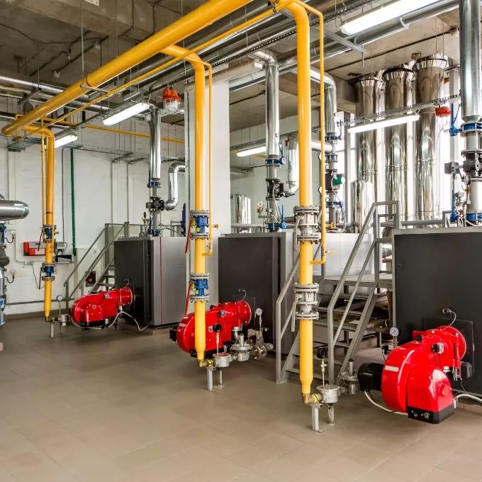 Commercial gas boiler house with yellow gas pipework and burners