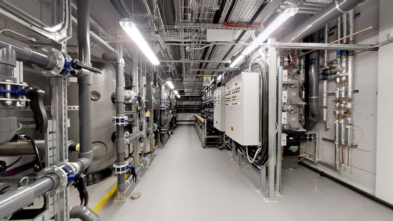 Plant room corridor with risers, service pipework and control panels