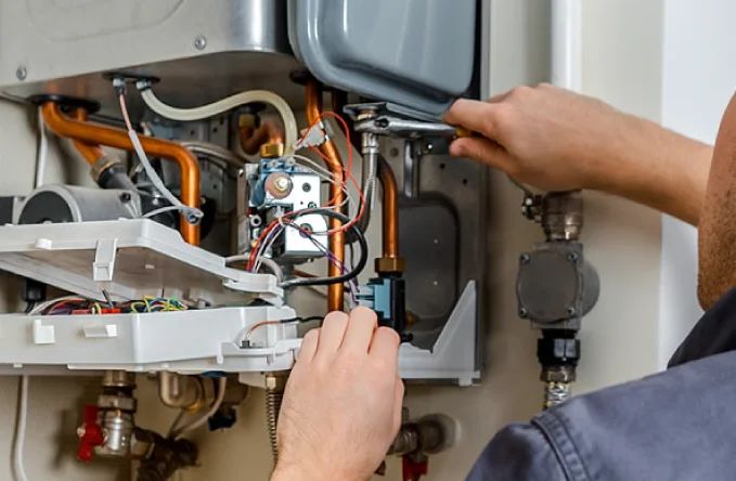 Engineer repairing the gas valve and wiring inside an open boiler