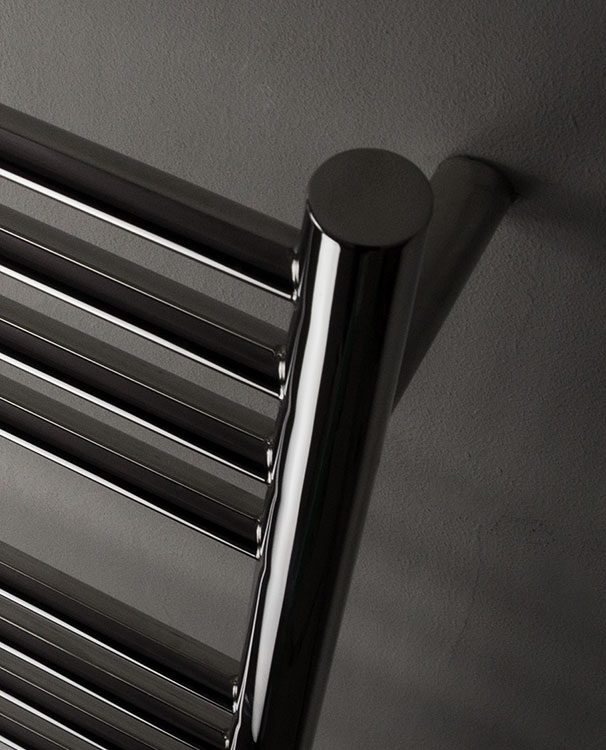 Close-up of a polished towel radiator against a dark wall