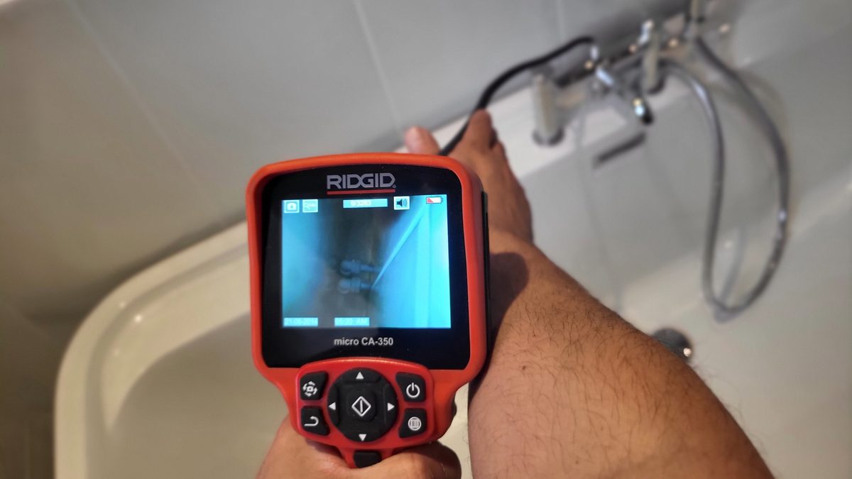Inspection camera showing pipework behind a bath panel