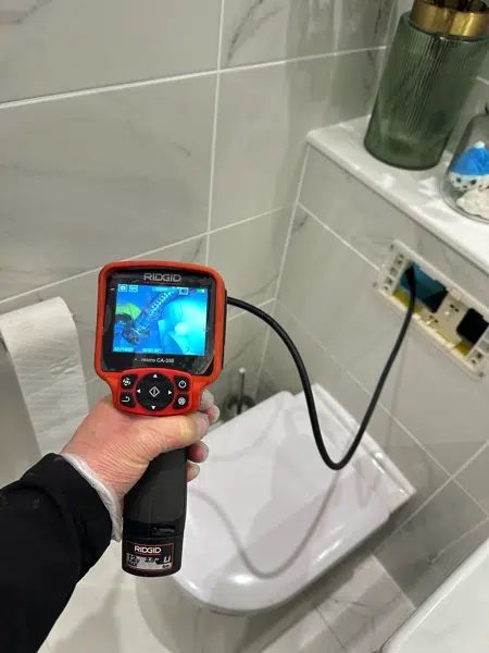 Inspection camera checking behind a wall-hung toilet