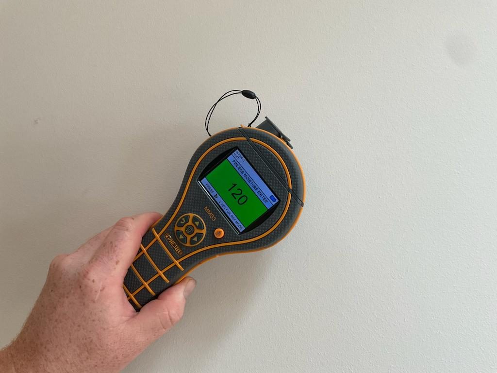 Pinless moisture meter held against a wall