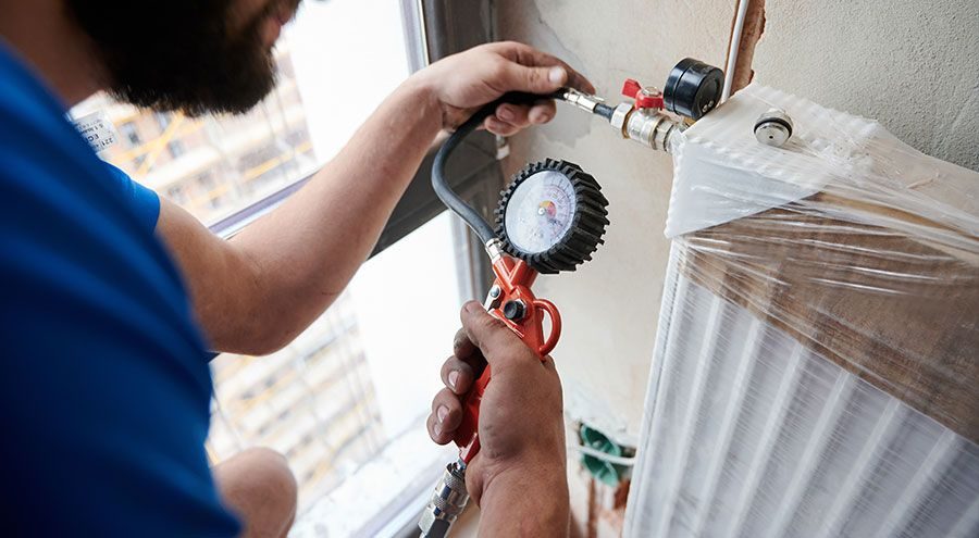 Engineer pressure testing a heating system at a radiator valve