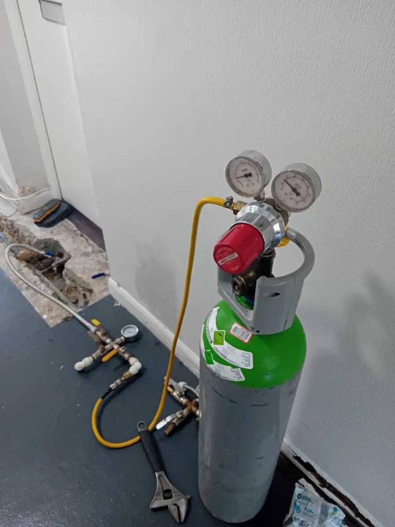Tracer gas cylinder and regulator connected for a leak test