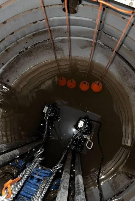 Looking down into a deep pump chamber with two pumps on chains and float switches